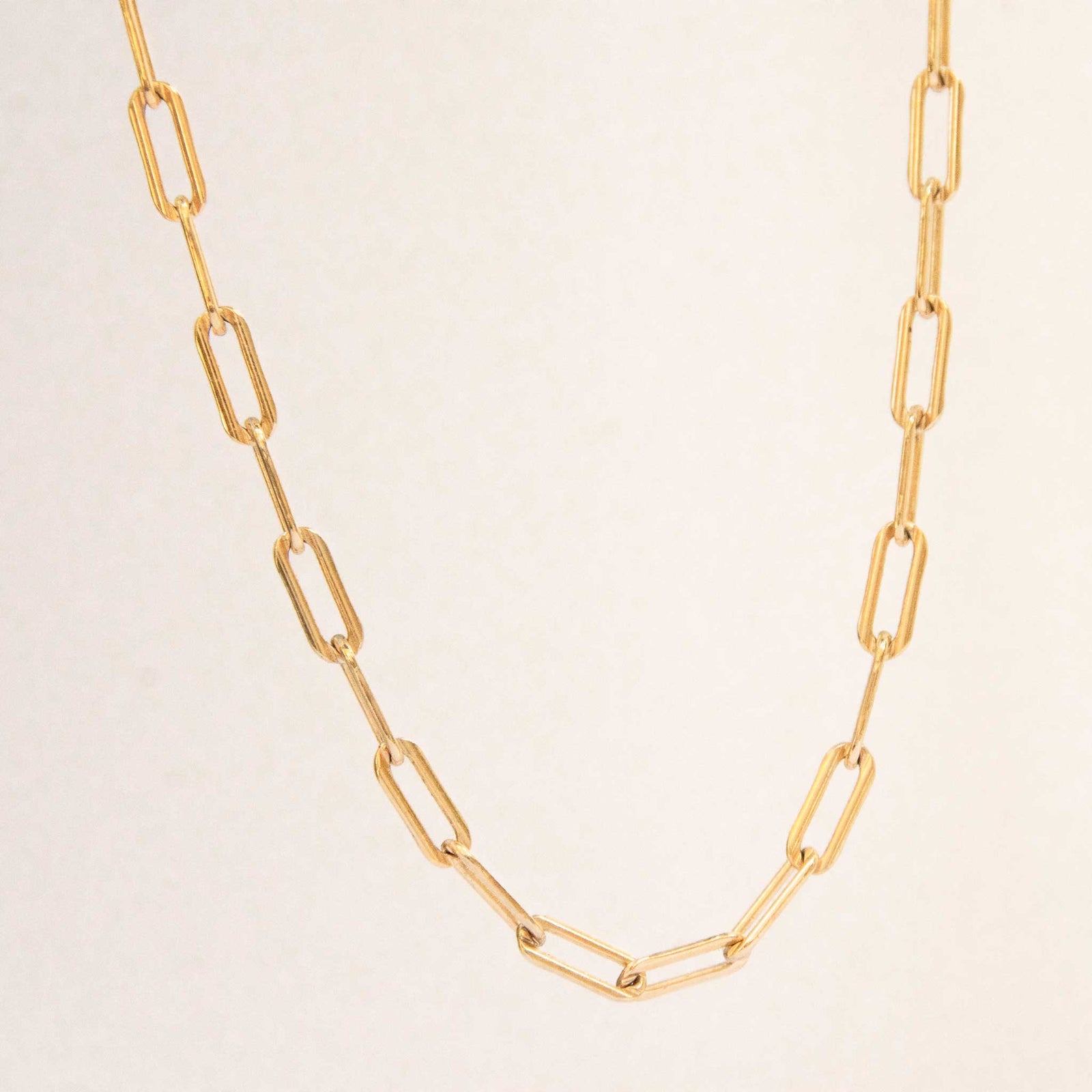 Half of the bold link necklace hanging with a white solid background.