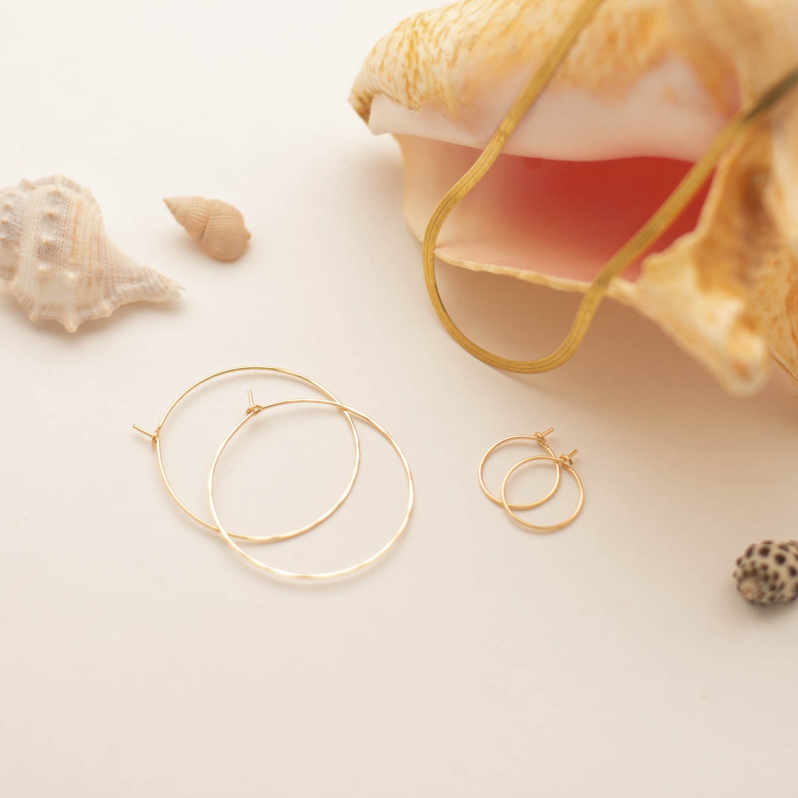 14k gold filled hoop earrings and herringbone necklace displayed with sea shells.