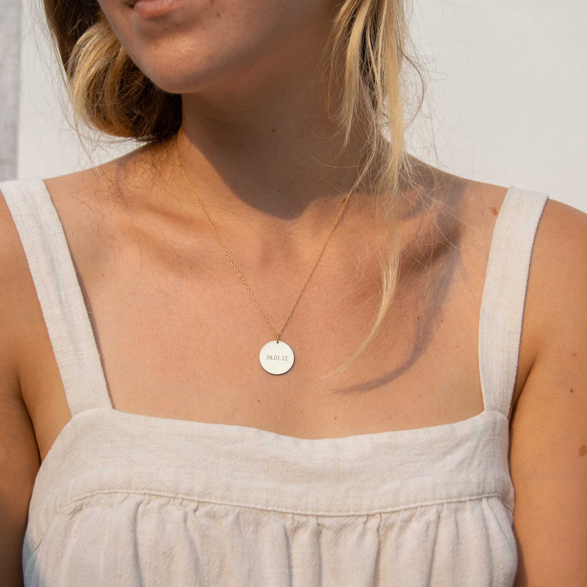 Woman is wearing the 19mm circle necklace and a white tank top looking to the left. 