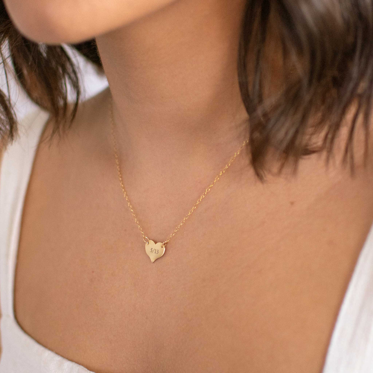 Woman is wearing a heart chain with 5/13 engraved in the ol&#39; serif font. 