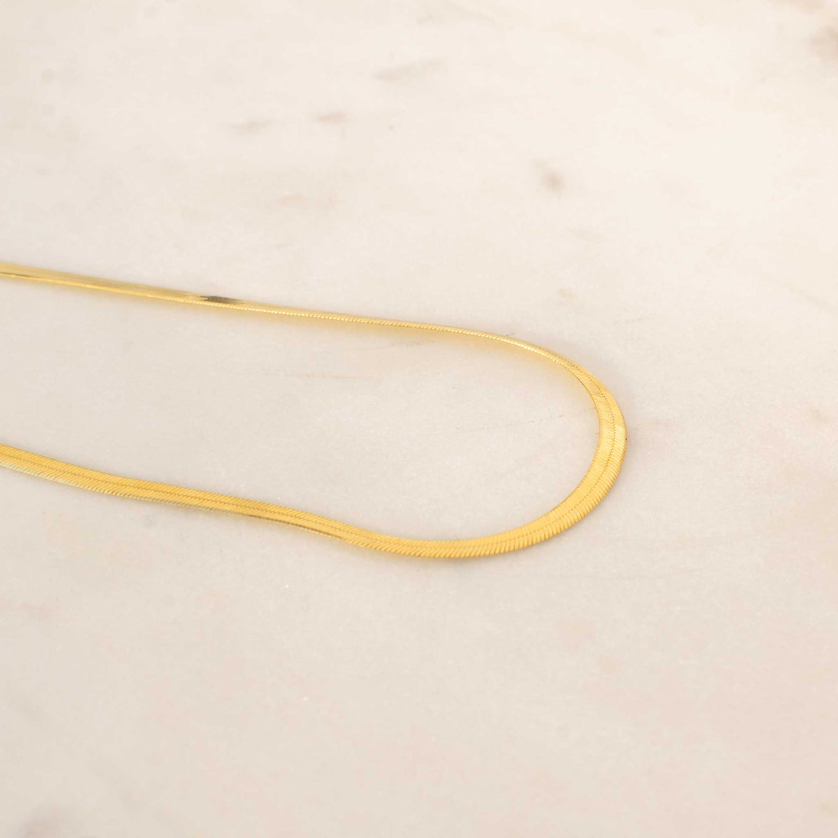 The U shape of the herringbone necklace from the left side perspective. 