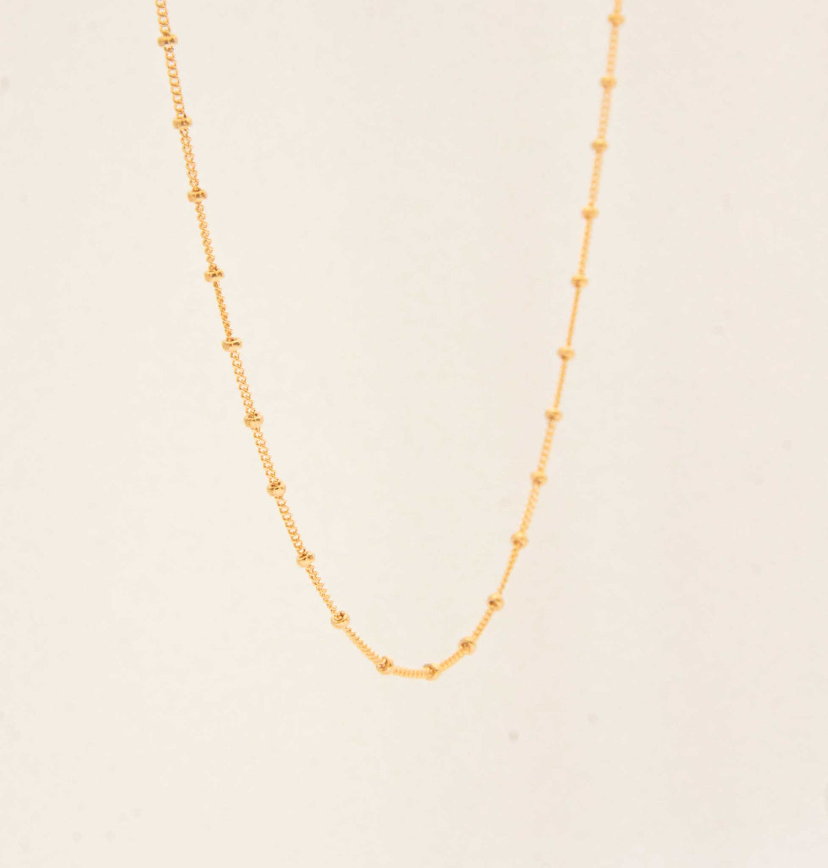 Half of the gold satellite chain hanging on a white solid background.