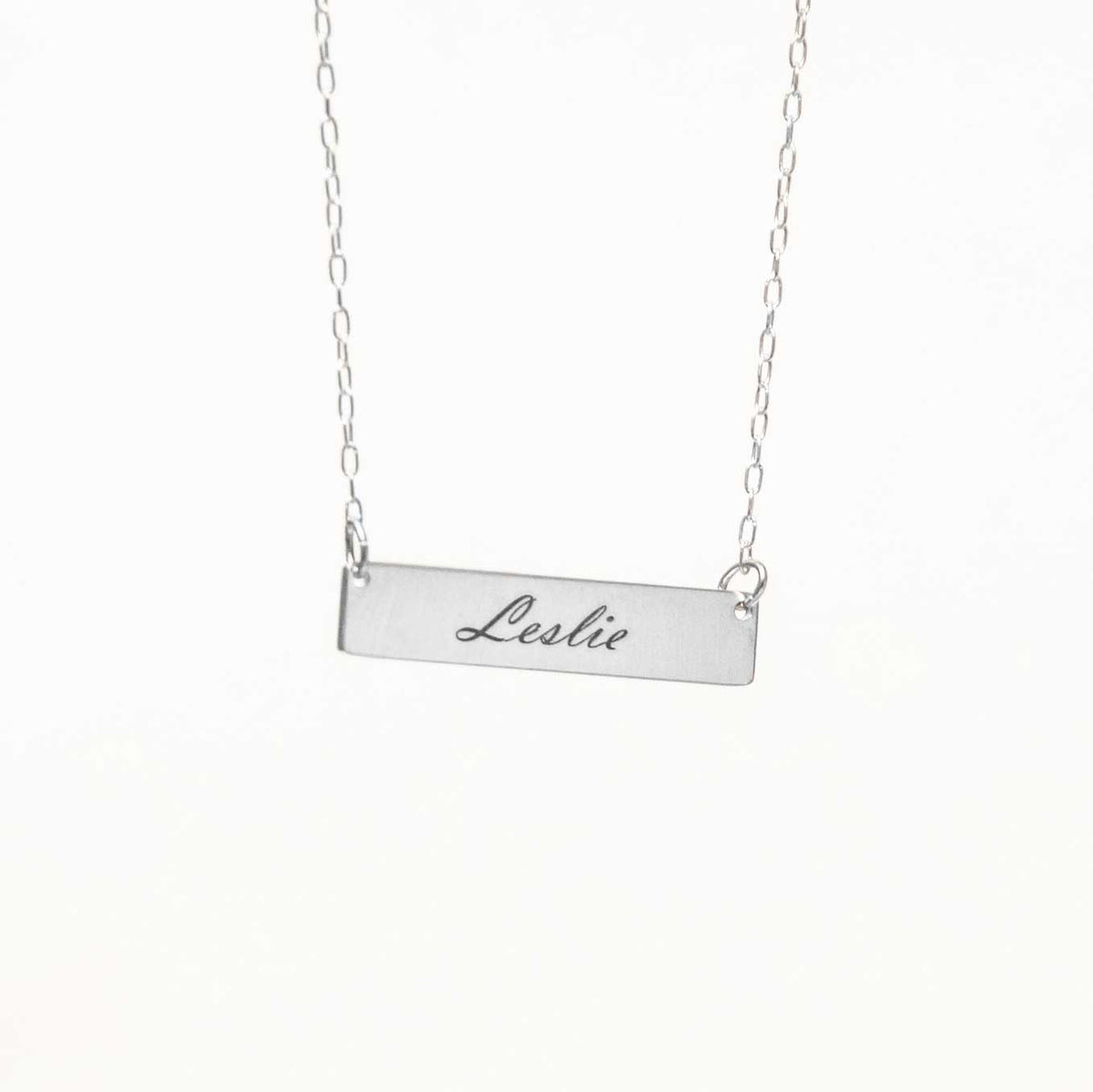 Rectangle necklace hanging from above with a solid white background. 