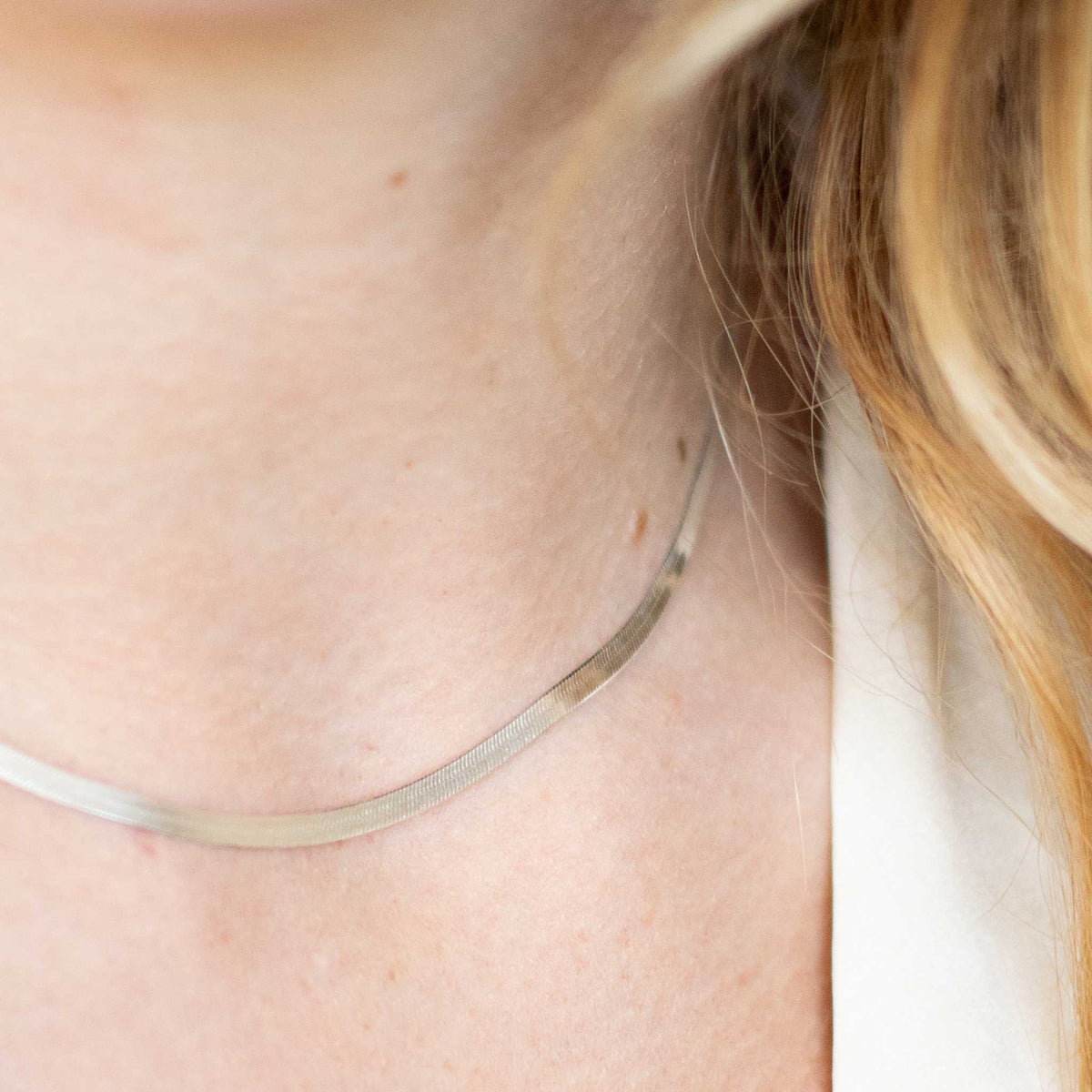 Up close shot of the silver herringbone with only the right side of the necklace in focus to highlight the details. 