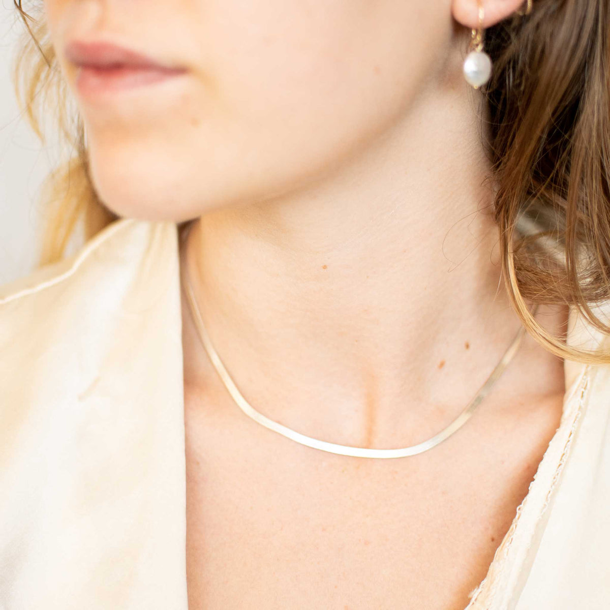 model wearing a silver herringbone chain looking to the left. 