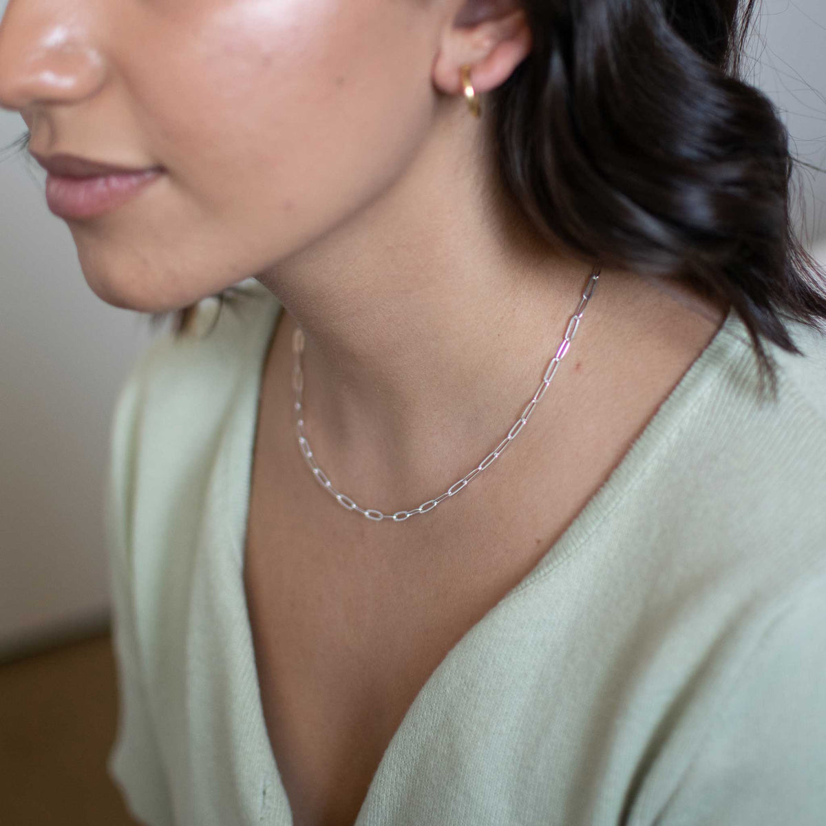 A left side view of the sterling silver chain necklace worn by model.