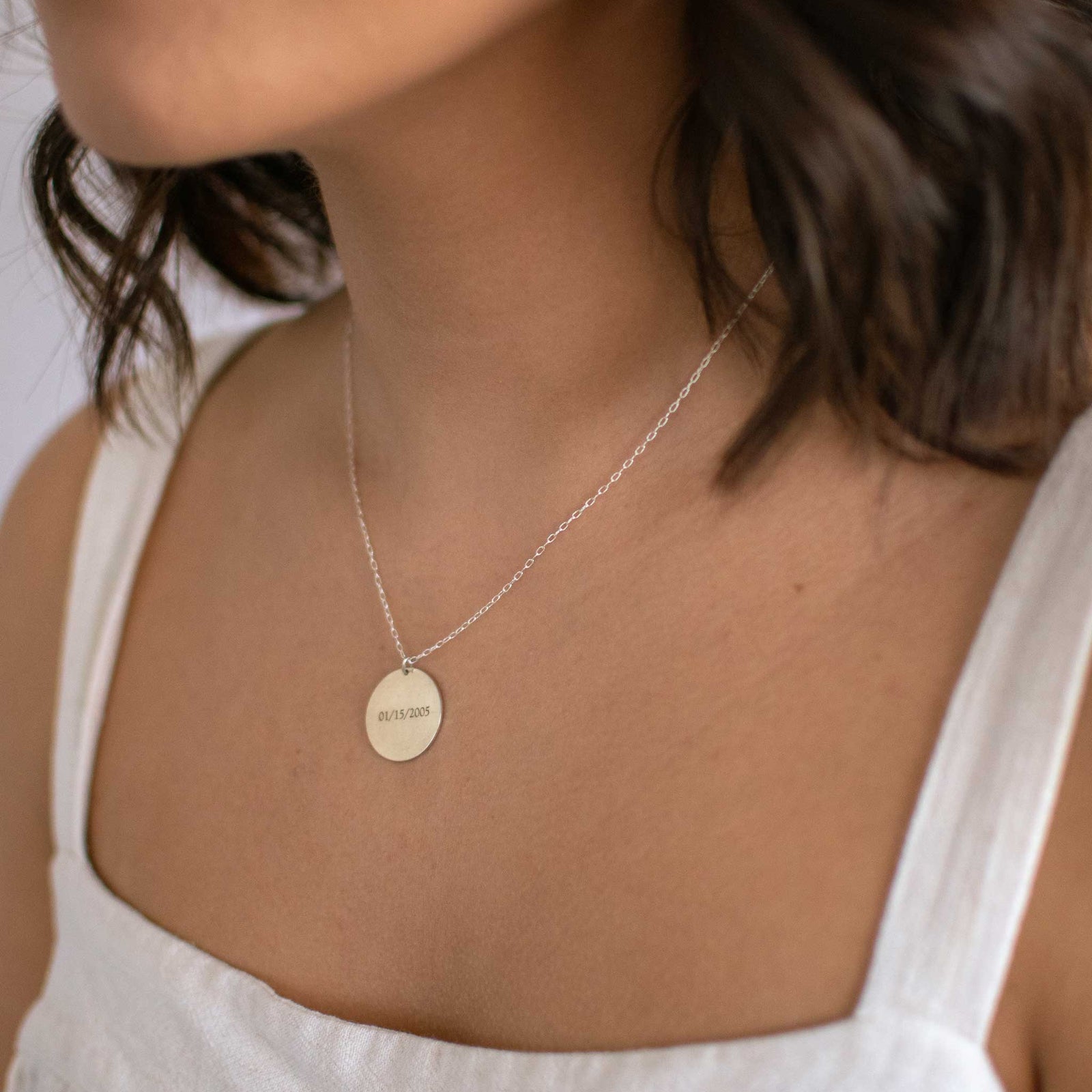 Close up of the 19mm circle pendant with a date engraved into it. 