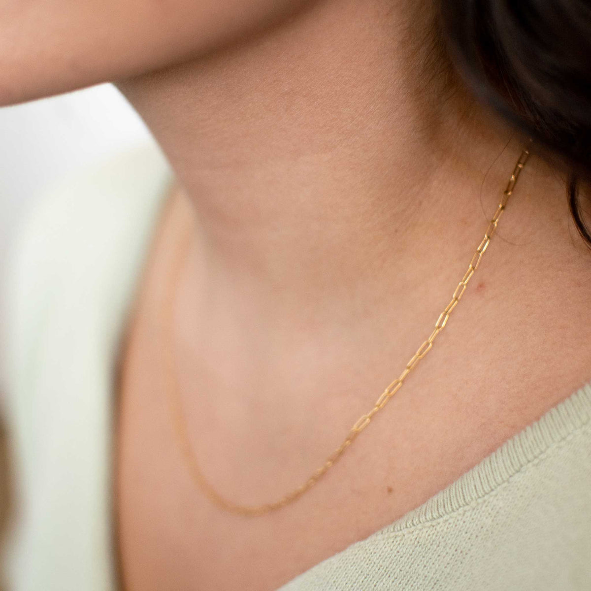 Up close of the small chain necklace worn by a woman.
